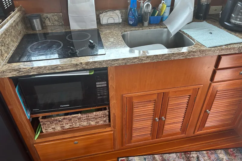  Yacht Photos Pics 2006 Mariner Orient kitchen with stove, sink, and microwave in wooden cabinetry.